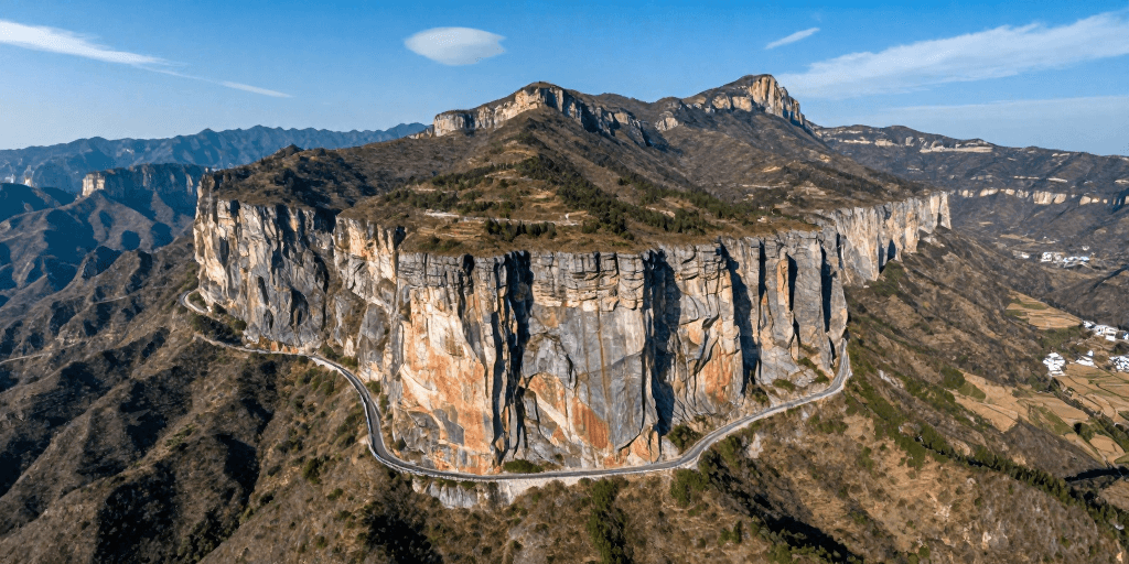 摄影作品素材：险峻山崖上的蜿蜒公路，壮丽自然光影