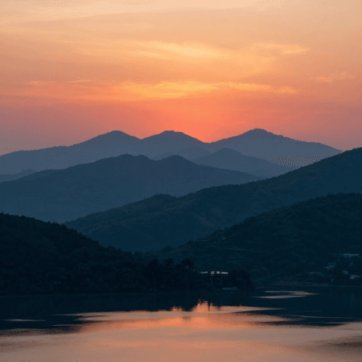 背景装饰素材：橘红天空下的群山剪影与水面倒影，宁静祥和的日出美景