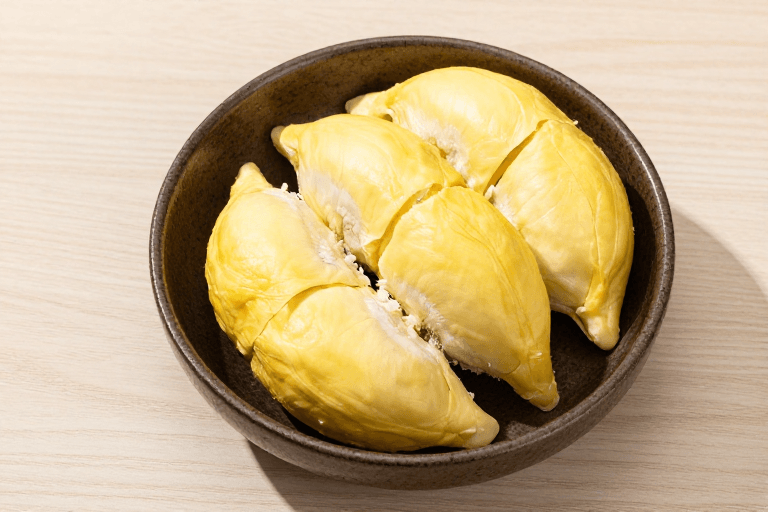 木质桌面素材：金黄榴莲果肉特写：自然光影下的陶碗美食