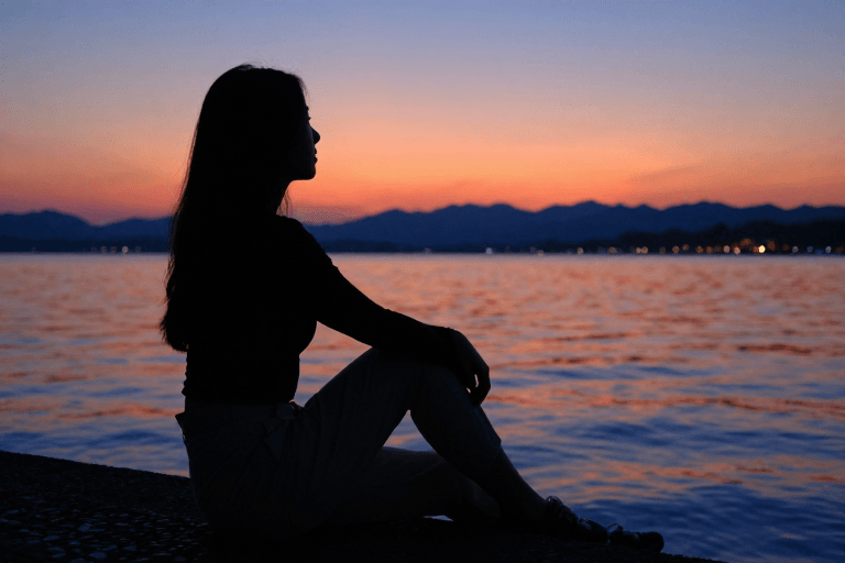 黄昏氛围素材：剪影湖畔女子凝望远方，逆光夕阳下的动人瞬间