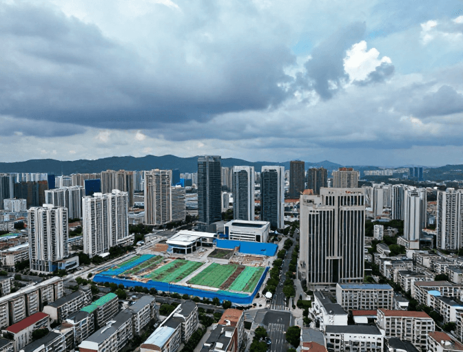冷调摄影素材：阴云笼罩下的现代城市：蓝绿施工区域与高层住宅交织