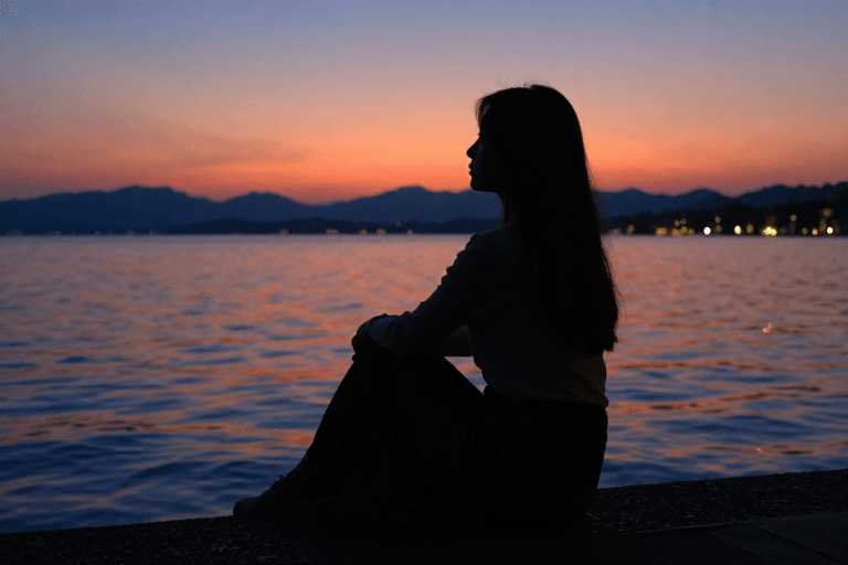 剪影艺术素材：日落湖畔剪影：长发女子的凝望与宁静时光